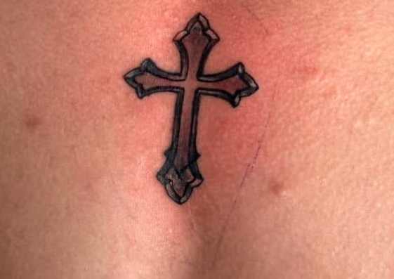 Cover-up auf der Brust: neues schwarzes Kreuz über einem alten Kreuz-Umriss
