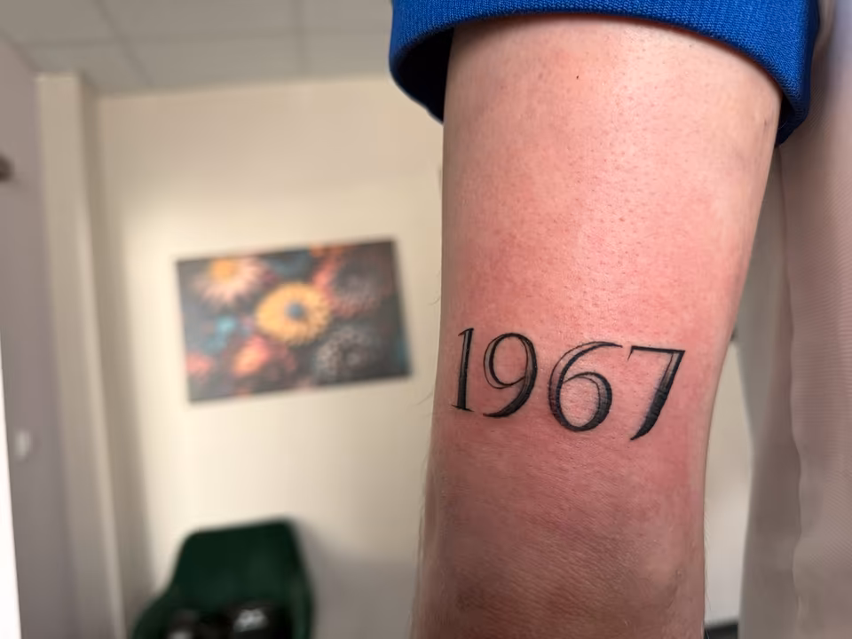 Jahreszahl 1967 in Serifenschrift am Unterarm