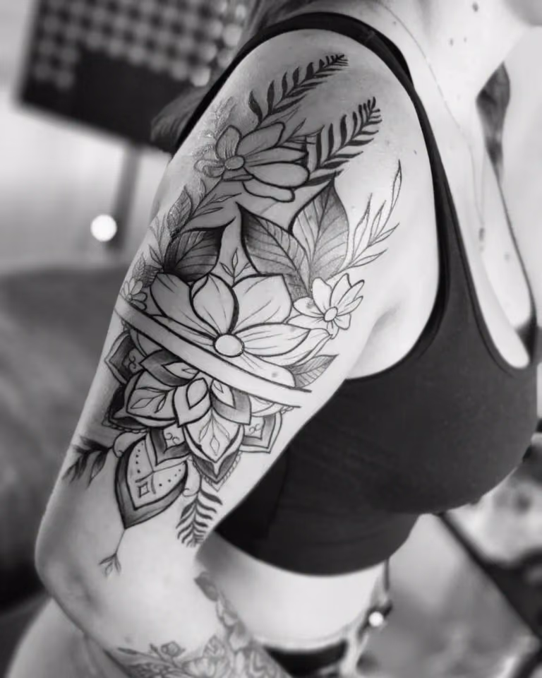 Blüten und Blätter über einem Mandala-Ornament am Oberarm