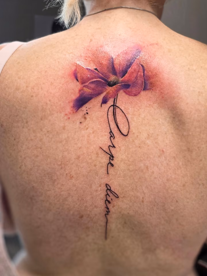 Aquarell-Blüte in Violett und Rosa mit Schriftzug Carpe diem entlang der Wirbelsäule