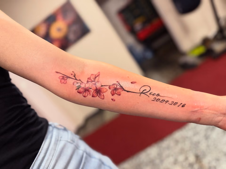 Kirschblütenzweig in Rosa mit Name Rico und Datum am Unterarm
